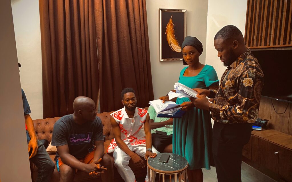 Godwin Harrison (L; seated) on the Hug Media Concept crew, including creative head Kelvin Okoroji (R; standing) and production head Uche Ebenezer.